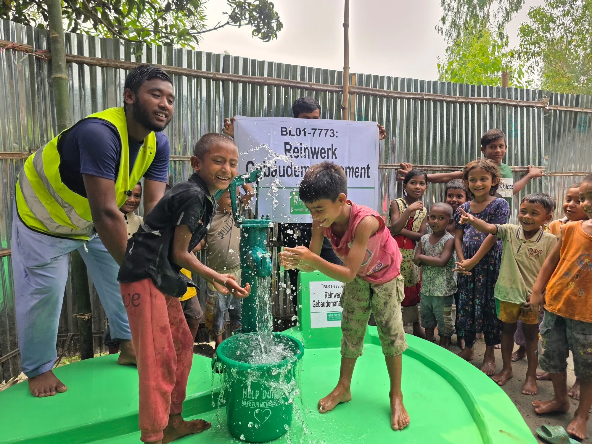 Wasser fließt aus dem neuen Brunnen in Bangladesch
